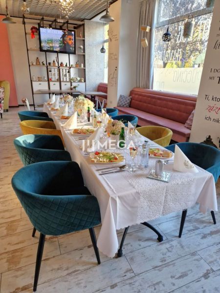 Stylové gastro prostory s dekorativní výzdobou, podlaha s dřevěným dekorem a elegantní židle.