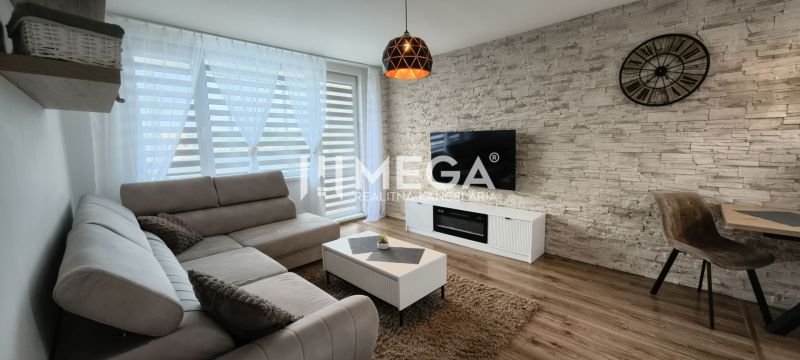 Obývací pokoj v 3-pokojovém bytě, s podlahou s dřevěným dekorem a TV na kamenné stěně.