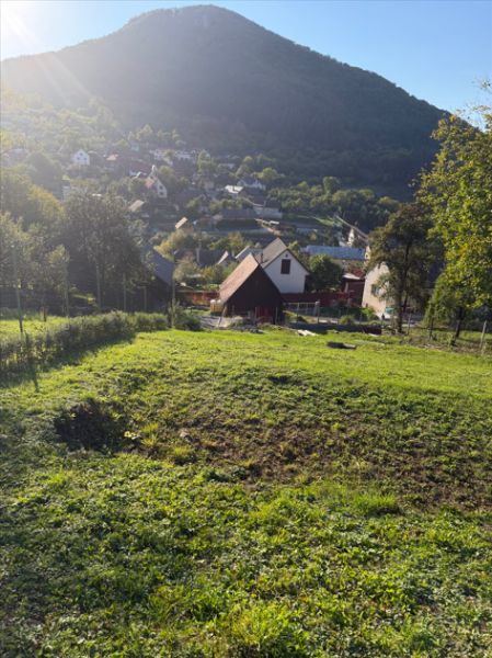 Pozemek na bydlení v Košeckém Podhradí obklopený přírodou a domy, pod vrcholy hor.
