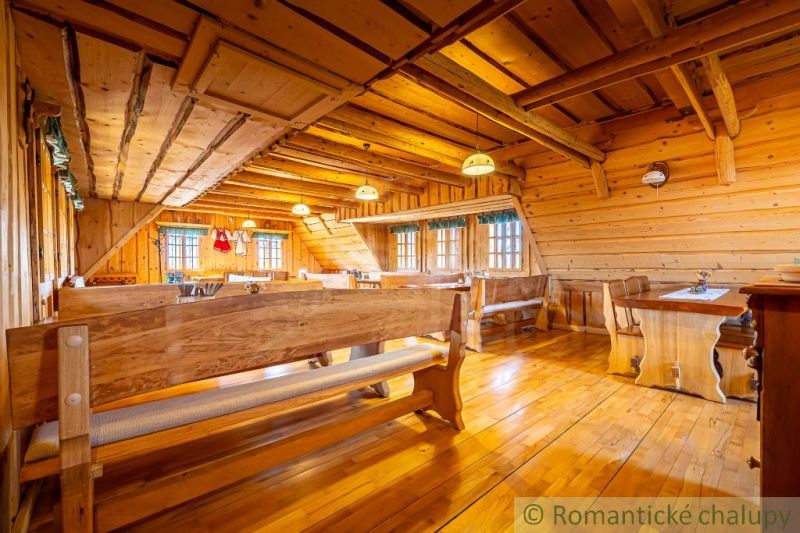 Interiér rodinného domu s dřevěnými stěnami, lavicemi a podlahou s dřevěným dekorem.