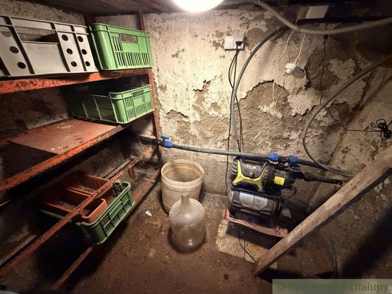 Úložný prostor s policemi a plastovými přepravkami na chatě.