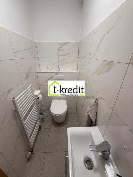 Koupelna v rodinném domě s bílými obklady a umyvadlem.
