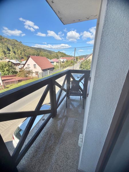 Balkon s výhledem na ulici Centrum v Oščadnici obklopený zelení a domy, 1-pokojový byt.
