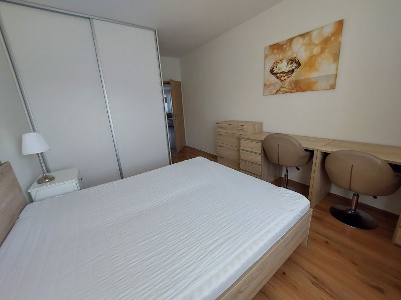 Ložnice s podlahou s dřevěným dekorem, postelí, pracovním stolem a šatníkovými skříněmi v 3-pokojovém bytě.