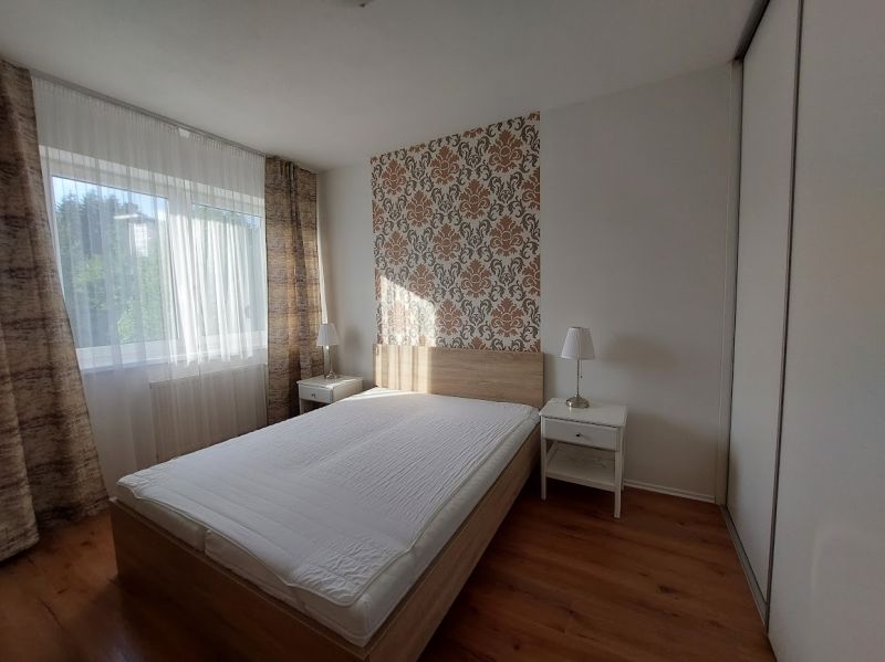 Ložnice s postelí, tapetou a podlahou s dřevěným dekorem ve 3-pokojovém bytě.
