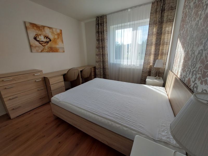 Ložnice s velkou postelí, podlahou s dřevěným dekorem a dekorativním obrazem v 3-pokojovém bytě.