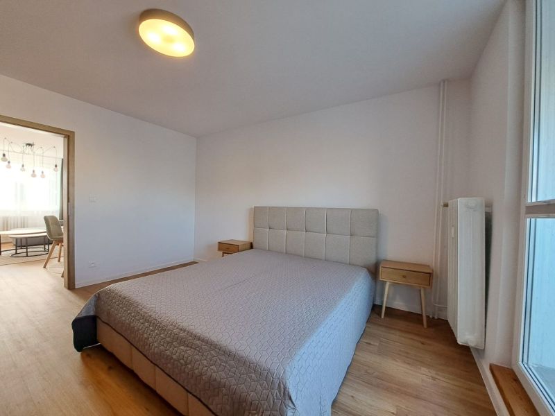 Ložnice s postelí a nočními stolky, podlaha s dřevěným dekorem v 2-pokojovém bytě.