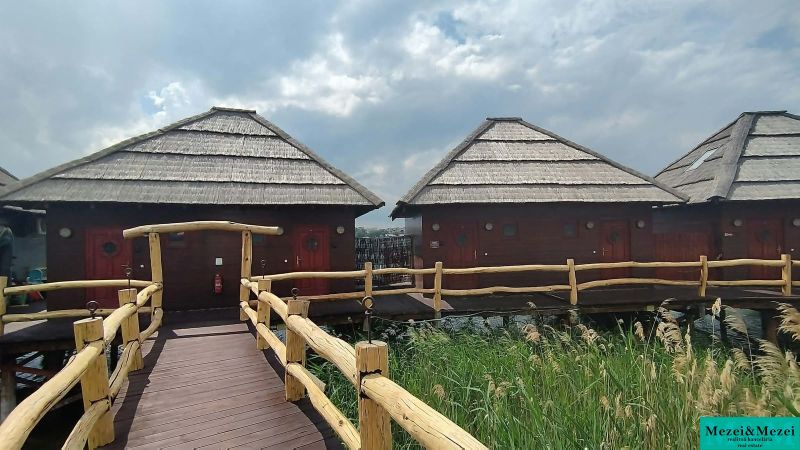 Dřevěné chaty nad vodní hladinou s doškovými střechami u seneckých jezer.