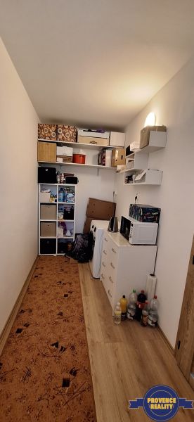 Kompaktní komora s regály, skříní a podlahou s dřevěným dekorem ve 3-pokojovém bytě.