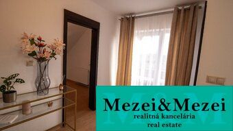 Interiér rodinného domu s dekorativním stolkem a oceněními realitní kanceláře.