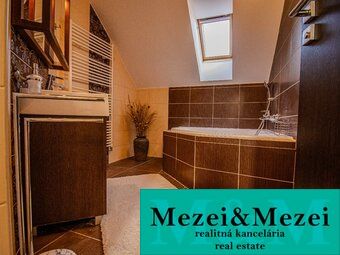 Koupelna v rodinném domě s vanou a dřevěným dekorem na nábytku.