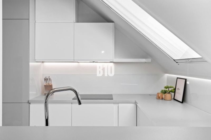 Kuchyně v podkroví se střešním oknem a minimalistickým designem v 2-pokojovém bytě.