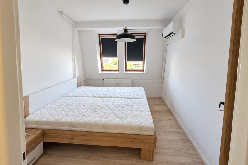 Ložnice s postelí, klimatizací a podlahou s dřevěným dekorem v 2pokojovém bytě.