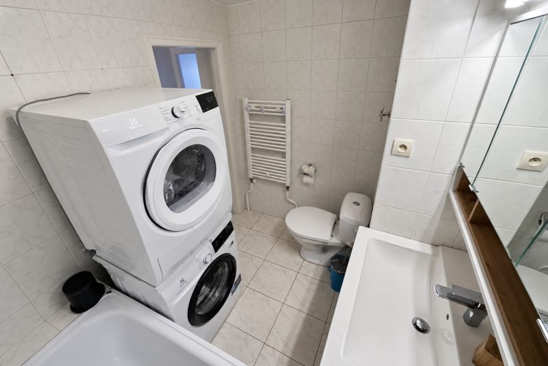 Koupelna se spotřebiči a sanitou v 2-pokojovém bytě, keramické obklady a dlažba.