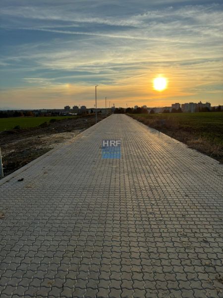 Zpevněná cesta na Vinohradech v Senici za soumraku s výhledem na město.