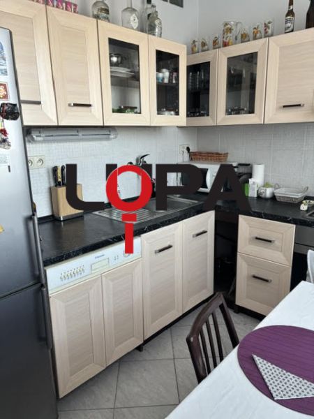 Kuchyně v 2-pokojovém bytě s dřevěným dekorem nábytku a světlými obkladačkami.