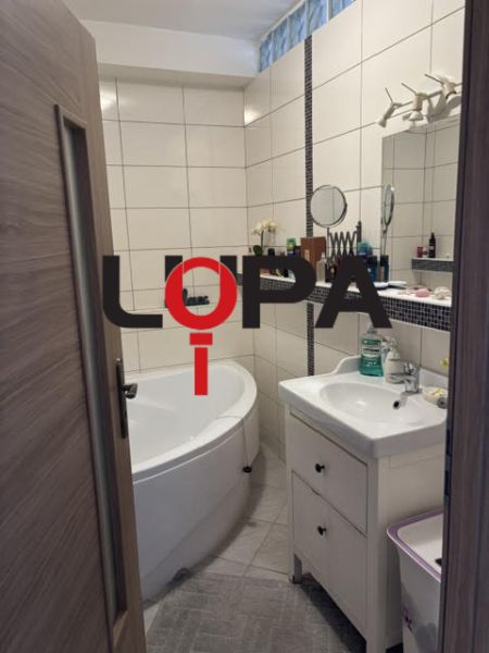 Koupelna v 2-pokojovém bytě s vanou, umyvadlem a bílými obkladačkami.