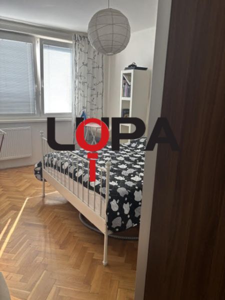 Ložnice v 2pokojovém bytě s postelí a podlahou s dřevěným dekorem.