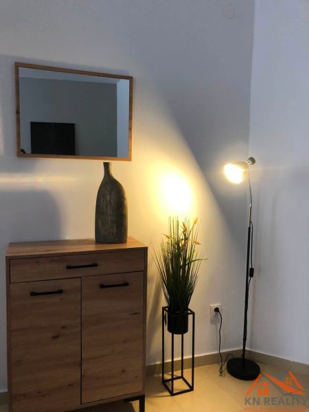 Zrcadlo, skříňka s podlahou s dřevěným dekorem a lampa vytvářejí atmosféru ve 2-pokojovém bytě.
