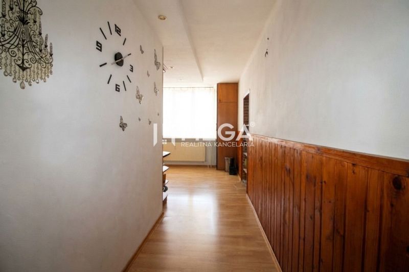 Chodba v 3-pokojovém bytě s podlahou s dřevěným dekorem a nástěnnými hodinami.