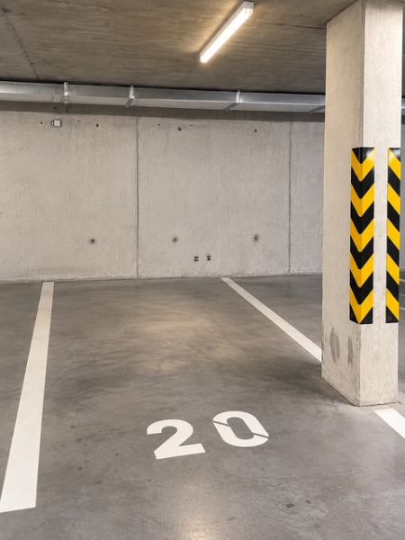 Podzemní garáž s betonovou podlahou a označením parkovacího místa číslo 20.