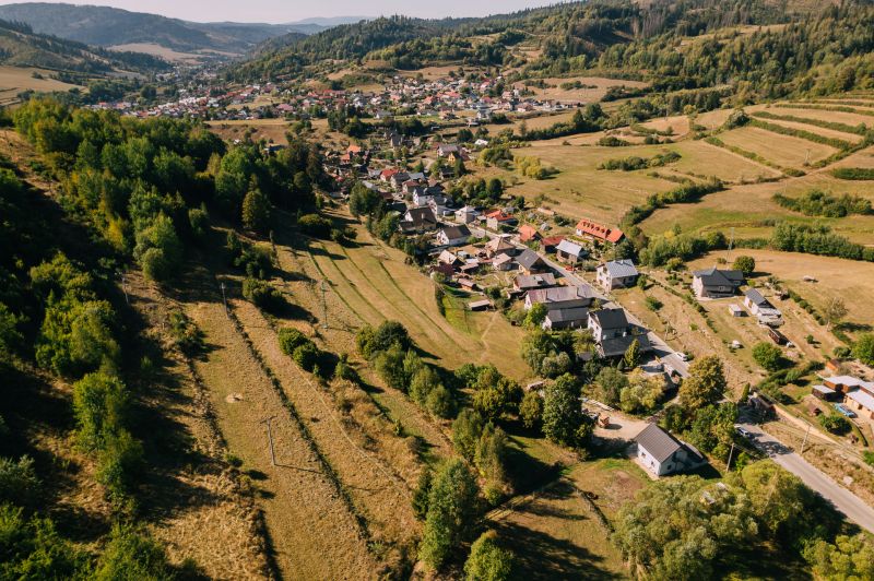 Letecký pohled na domy a louky v Čiernom Balogu, Školské ulici obklopené rekreačními pozemky.