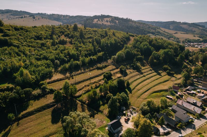 Letecký pohled na zelené kopce a domy na Školní ulici v Černém Balogu.