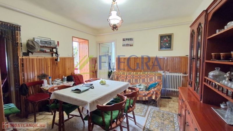 Obývací pokoj v rodinném domě s jídelním stolem a vitrínou.