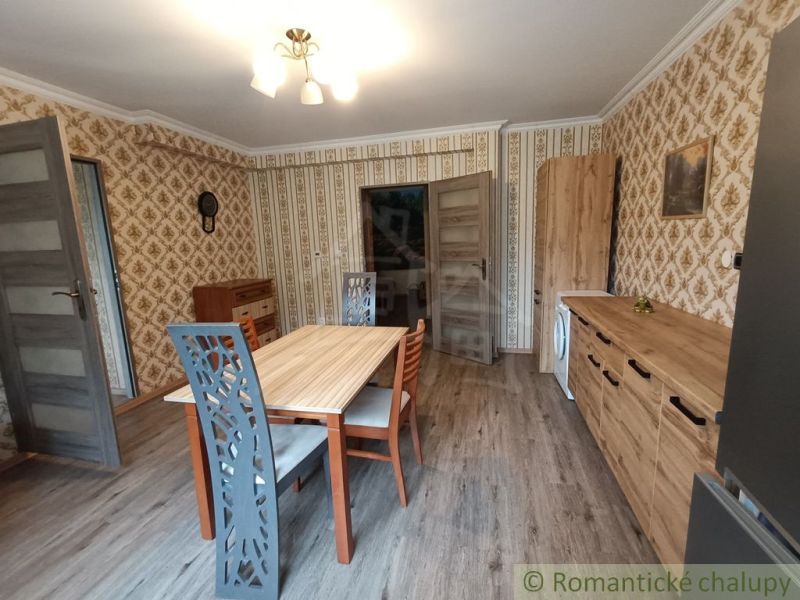 Jídelna v rodinném domě se vzorovanou tapetou a podlahou s dřevěným dekorem.