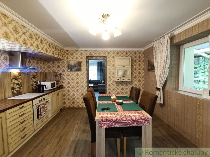 Interiér rodinného domu s podlahou s dřevěným dekorem, jídelním stolem a tapetami.