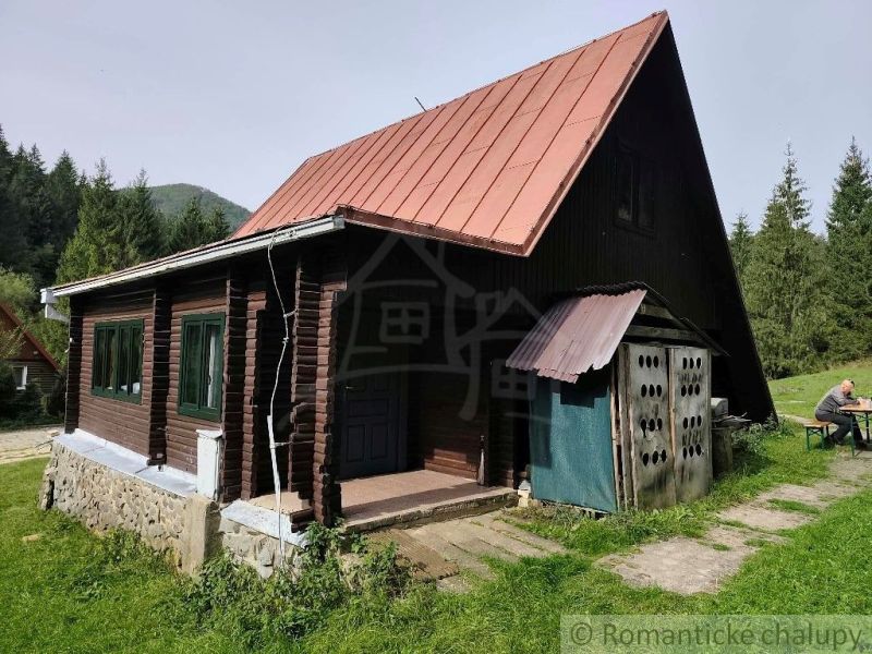Chata v Rajecké Lesné s plechovou střechou a dřevěnými stěnami obklopená přírodou.