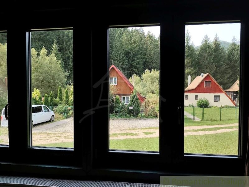 Výhled na chaty v Rajecké Lesné, obklopené zelení a auty.