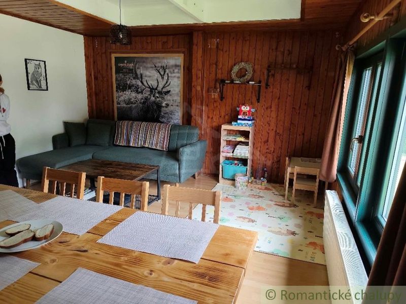 Dřevěný interiér chaty s pohovkou, stolem a hračkami na podlaze s dřevěným dekorem.