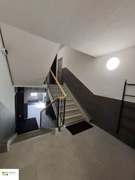 Schodiště bytového domu ve 3-pokojovém bytě s moderními dlaždicemi a zábradlím.