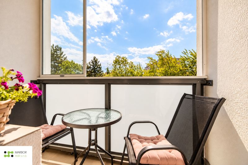Zařízený balkon s kulatým stolem a dvěma židlemi ve 3-pokojovém bytě.