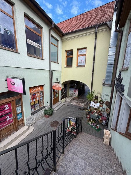 Schody vedou k obchodním prostorům v historickém centru Topoľčan, obklopeným obchody.