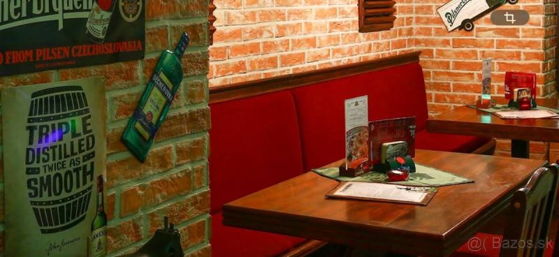 Cihlová stěna a dřevěný nábytek gastro prostorů s červenými sedačkami dodají útulnost.