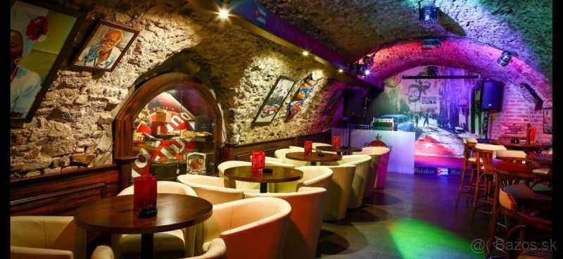 Bar v historických gastro prostorech s kamennými stěnami a podlahou s dřevěným dekorem.