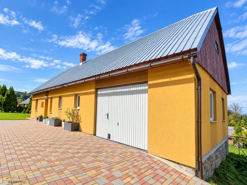Žlutý rodinný dům na ulici Košariská v Oščadnici s pestrobarevnou dlažbou.