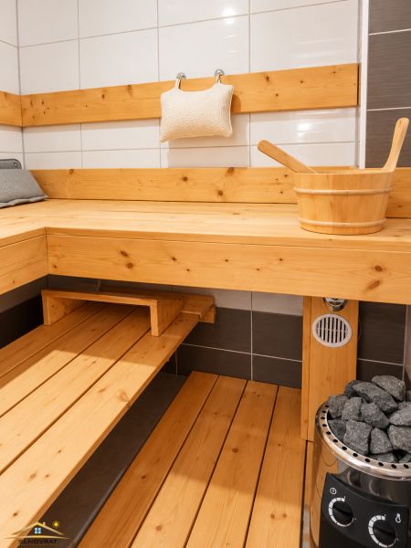 Sauna v rodinném domě s dřevěným obložením a kamny s kameny.