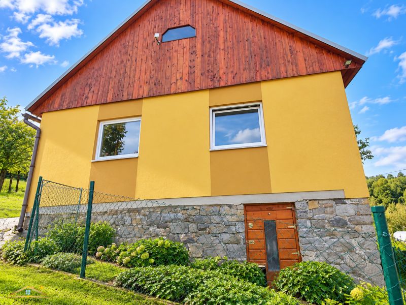 Rodinný dům na ulici Košariská v Oščadnici má žlutou fasádu a kamenný základ.