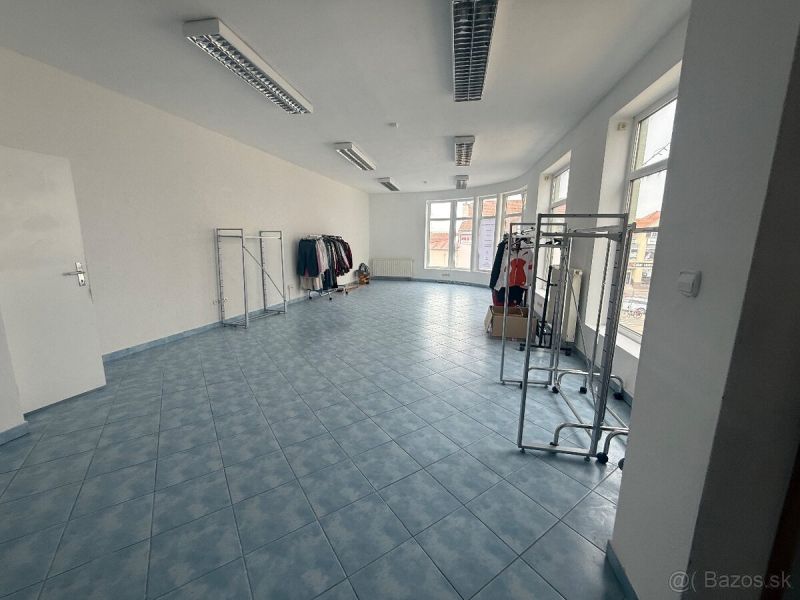 Obchodní prostory s modrou dlažbou a stojany na oblečení.