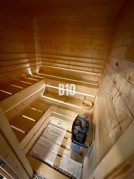 Dřevěná sauna v chatě s lavicemi a kamny na kameny.