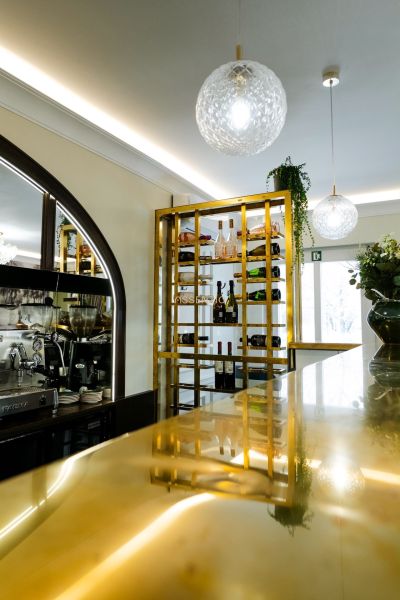 Elegantní vinotéka a bar v obchodních prostorách s moderním osvětlením a zlatými detaily.