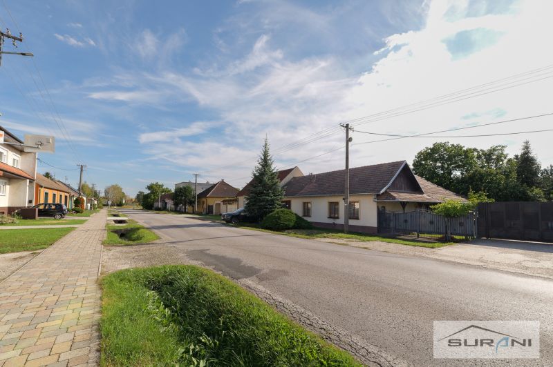 Rodinné domy na Hlavní ulici ve Štefanové s upravenou zahradou a jasnou oblohou.