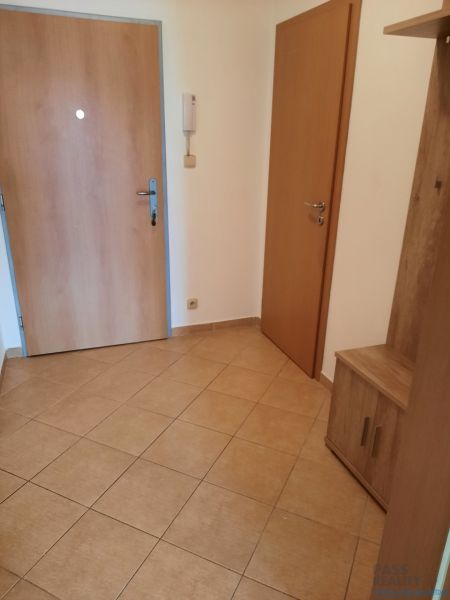 Vstupní chodba v 2-pokojovém bytě s dlažbou a dřevěnými dveřmi.