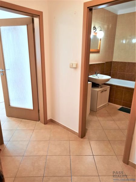 Chodba s dlažbou a výhledem na koupelnu ve 2pokojovém bytě.