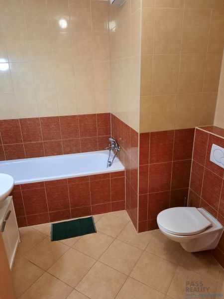 Koupelna s vanou a WC ve 2-pokojovém bytě, obklopená keramickými obklady.