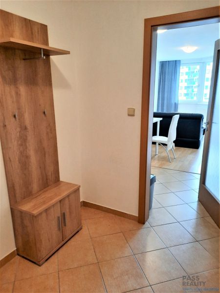 Předsíň v 2-pokojovém bytě s věšákovou stěnou a výhledem do obývacího pokoje s jídelnou.