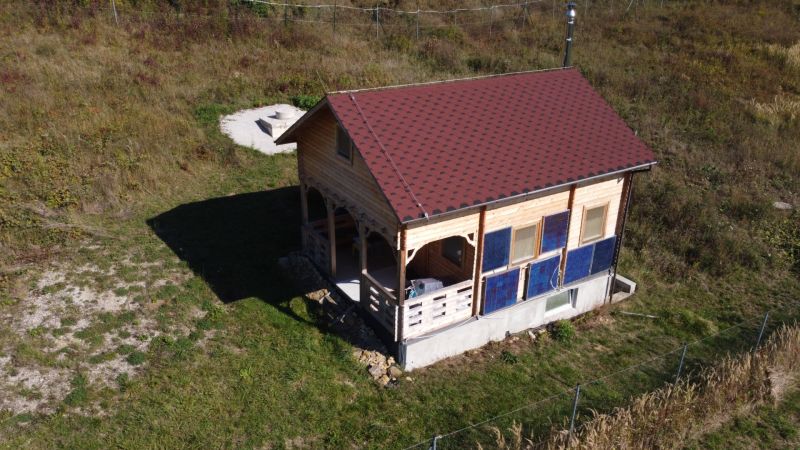 Chata v Horní Breznici s dřevěným obkladem a červenou střechou na zeleném pozemku.